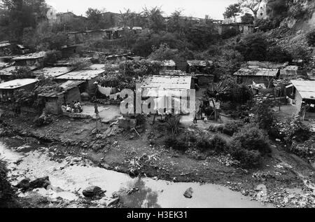 SAN SALVADOR, EL SALVADOR, MAY 1986: An inner city slum where houses are squeezed between a rubbish tip and a stream polluted with toxic chemicals.   Photo by Mike Goldwater Stock Photo