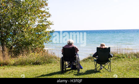 Two senior people sitting on the beach. Stock Photo
