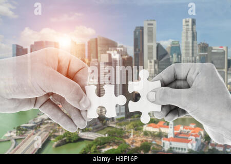Hands putting partnership puzzle pieces together on skyscraper building in background. Partnership network concept Stock Photo