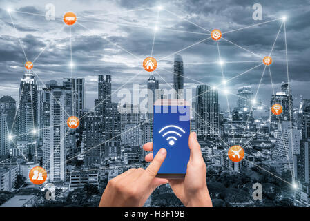 Hand holding smartphone with bangkok city scape and wifi network connection. Smart city network connection concept Stock Photo