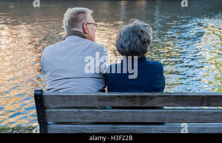 Utrecht, The Netherlands - August 6, 2016: Two People, a woman and a man, sitting on a bench and watching  at the water. Stock Photo
