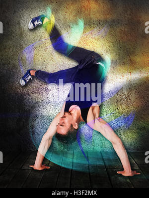 Break dancer doing handstand against colorful wall background Stock Photo