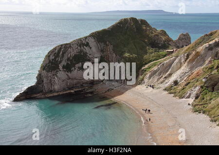 Looking towards a large rock outcrop on one end of a natural bay formed in the soft chalk with a shingle beach on a sunny day. Stock Photo