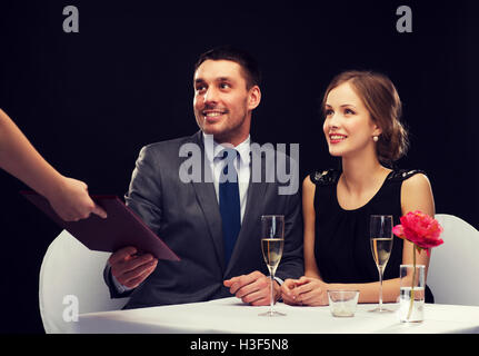 waiter giving menu to happy couple at restaurant Stock Photo