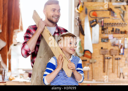 happy father and son with wood plank at workshop Stock Photo