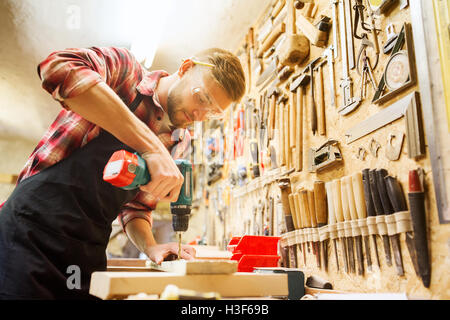 carpenter with drill drilling plank at workshop Stock Photo