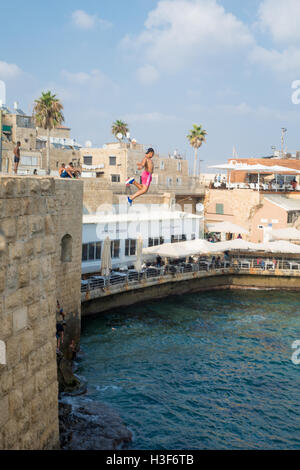 ACRE, ISRAEL - AUGUST 03, 2016: Young man jumps to the sea from the top of the ancient walls of Acre, Israel. Acre is one of the Stock Photo