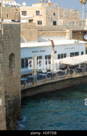 ACRE, ISRAEL - AUGUST 03, 2016: Young man jumps to the sea from the top of the ancient walls of Acre, Israel. Acre is one of the Stock Photo