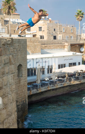 ACRE, ISRAEL - AUGUST 03, 2016: Young man jumps to the sea from the top of the ancient walls of Acre, Israel. Acre is one of the Stock Photo