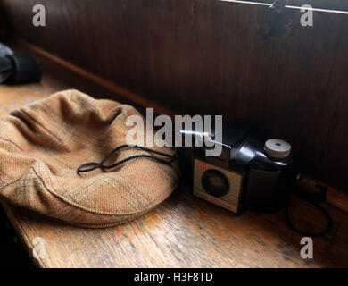 1st October 2016, tweed flat hat with old Kodak brownie 127 camera on a wooden bench, natural light Stock Photo