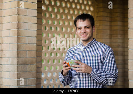 Portrait of young happy smiling man drinking water from spring, outdoors Stock Photo