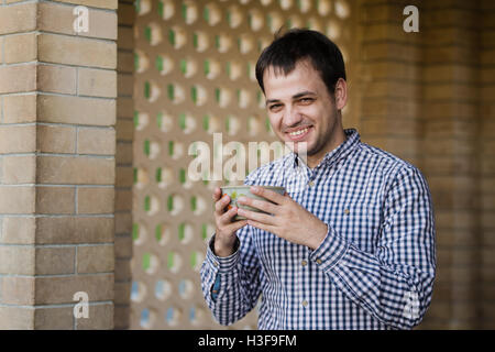 Portrait of young happy smiling man drinking water from spring, outdoors Stock Photo
