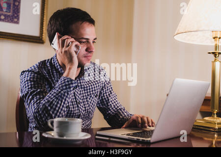 Young happy man talking on the phone at his workplace in office Stock Photo