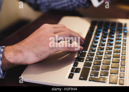 Close up male hands holding big smart phone while connecting to wireless, businessman using technology sitting at wooden desk Stock Photo