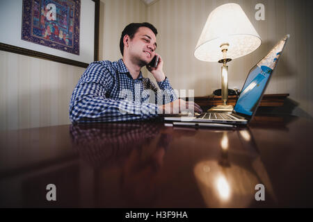 Young happy man talking on the phone at his workplace in office Stock Photo