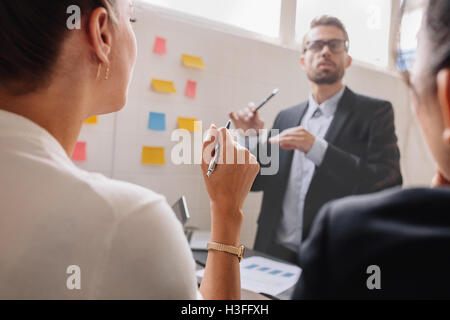 Close up shot of woman listening to businessman during a business presentation, with focus on hand of woman. Stock Photo