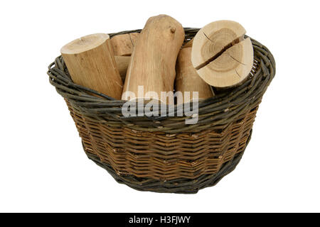Willow basket. Handmade, dark brown, woven willow basket containing logs. Isolated on a white background. Stock Photo