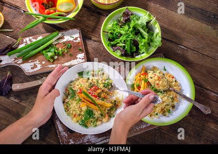 Woman Hands holding plate of Couscous with vegetables. View from above Stock Photo