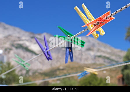 Different color clothes pegs on a washing line with the mountains of Samos in the background. Stock Photo