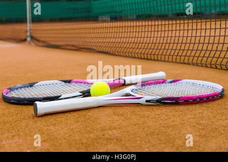 Side view on tennis rackets with a tennis ball on  clay court outdoors Stock Photo