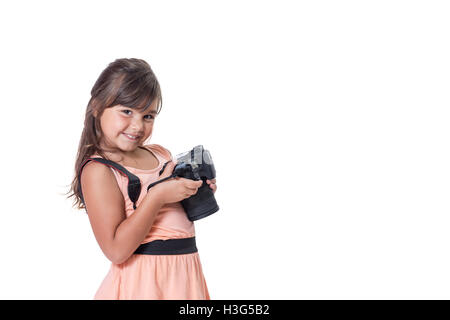 Smiling long hair little girl is holding SLR camera. The girl is slightly skewed and is looking at the camera. Stock Photo