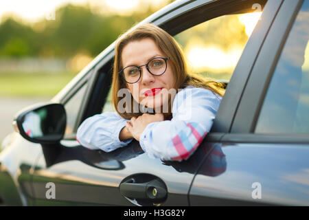 Young happy woman sitting in a car - concept of buying a used car or a rental car Stock Photo