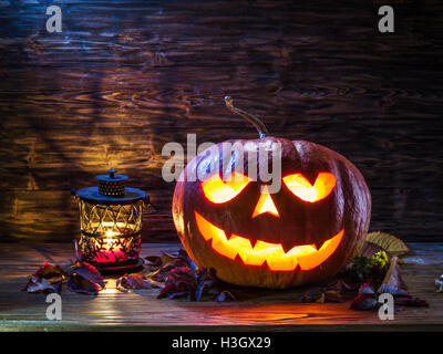 Grinning pumpkin lantern or jack-o'-lantern is one of the symbols of Halloween. Halloween attribute. Wooden background. Stock Photo