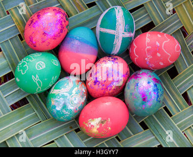Woven green palm tree leaves with a group of colorfully dyed eggs with metallic accents resting on top. Stock Photo