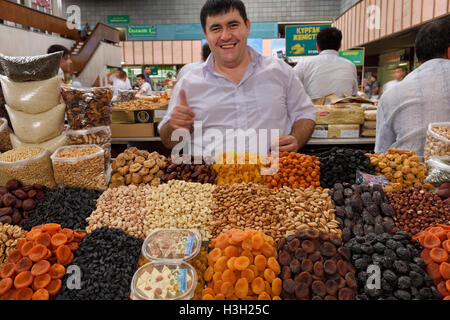Smiling vendor with gold teeth in dried fruits and nuts at Green Bazaar Almaty Kazakhstan Stock Photo