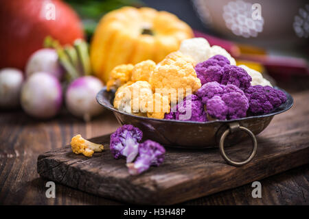 Colorful cauliflower in rustic bowl on wooden board Stock Photo