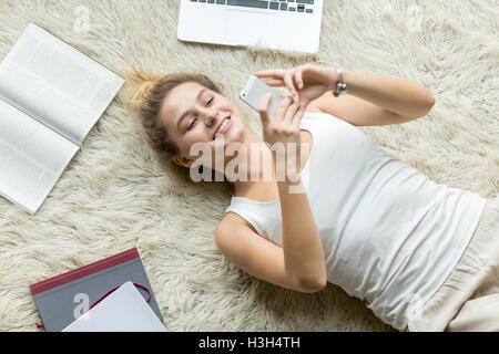 Top view of young woman messaging on phone at home Stock Photo