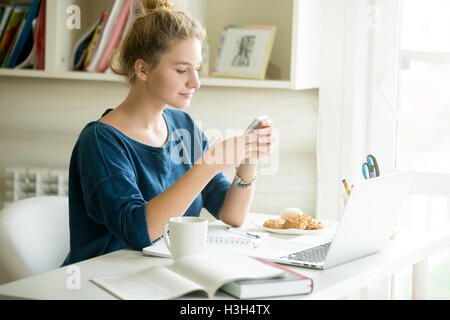 Happy woman messaging in cozy home-office Stock Photo