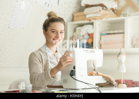 Portrait of smiling attractive woman at sewing machine Stock Photo