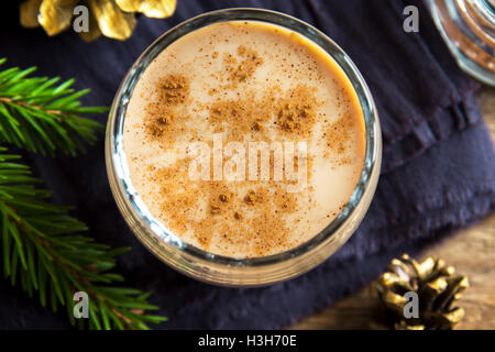 Eggnog with cinnamon in glass close up with Christmas decor  - homemade traditional festive drink for Christmas time Stock Photo