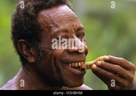 Papuan man eating a grub. Stock Photo