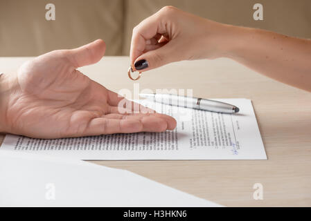 Wife and husband signing divorce documents, woman returning wedding ring Stock Photo