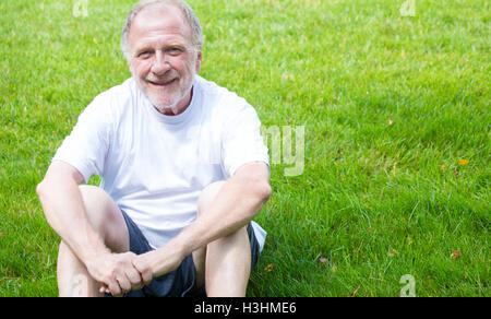 Closeup portrait of happy, confident, cheerful, smiling senior mature man in white shirt and shorts, sitting down Stock Photo