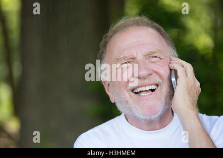 Closeup portrait, older, happy ecstatic man with wide open mouth talking on cell phone, isolated outdoors background Stock Photo