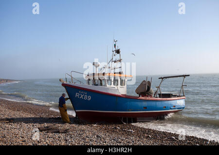Traditional wooden fishing boat being pull out the sea onto the shingle beach at the Stade, Hastings, East Sussex, UK Stock Photo
