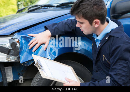 Auto Workshop Mechanic Inspecting Damage To Car And Filling In Repair Estimate Stock Photo