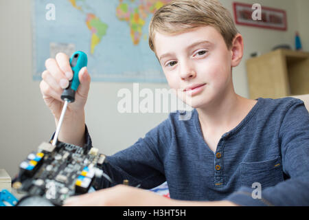 Boy Assembling Robotic Kit In Bedroom Stock Photo