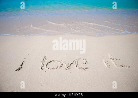 Word i love it handwritten on sandy beach with soft ocean wave on background Stock Photo