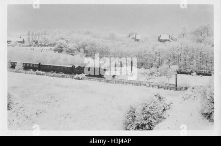 Steam train (GWR 6000 Class) and carriages rushing through a snow bound landscape in the winter. Photographed 12th December 1950 near Aughton Park Lancashire Stock Photo