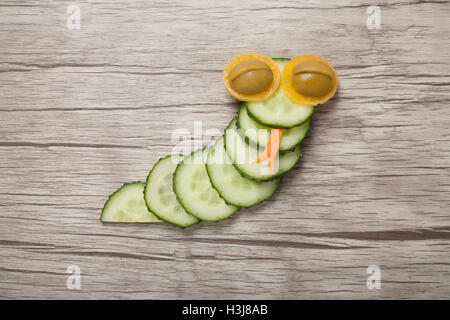 Funny snake made of cucumber on wooden background Stock Photo