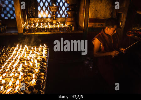 Buddhist monk at a candle lit chapel in Swayambhunath Monkey temple. Kathmandu, Nepal Stock Photo