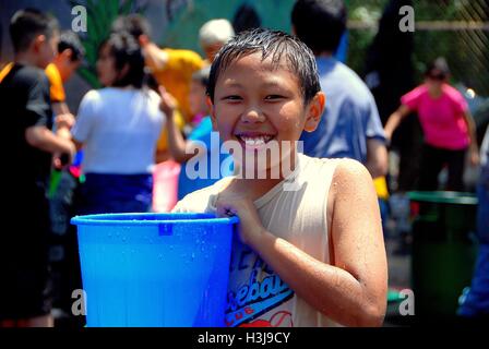 New York City:  Smiling Asian boy holding a blue bucket filled with water at the Burmese Thingyan Festival in Chinatown Stock Photo