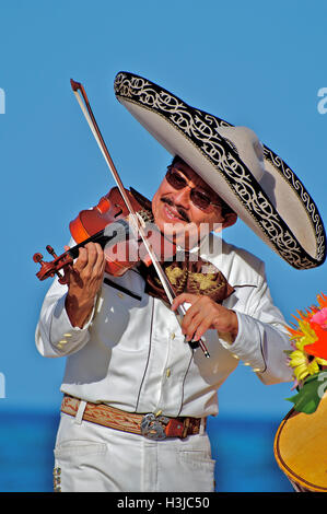 Mariachi Fiddler Performs on Sunny Beach during Wedding wearing a Sombrero Hat & White Suite with Gold Bucket in Mexico Stock Photo