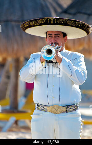 Mariachi Trumpet Player Performs on Sunny Beach during Wedding wearing a Sombrero Hat & White Suite with Gold Bucket in Mexico Stock Photo