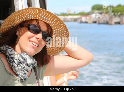 Smiling young woman with straw hat and sun glasses on the ship while traveling Stock Photo