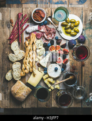 Wine and snack set with various wines in glasses, meat variety, bread, sun-dried tomatoes, honey, green olives, figs, nuts and f Stock Photo